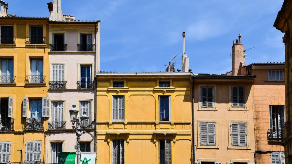 Historic pastel-colored buildings under blue sky in Aix-en-Provence, France.